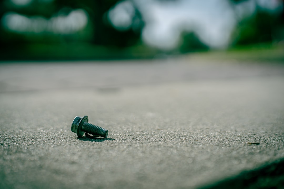 a-single-screw-lies-on-a-concrete-surface-esqyaqwfv2m